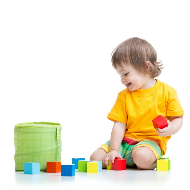 child putting colorful blocks into a container
