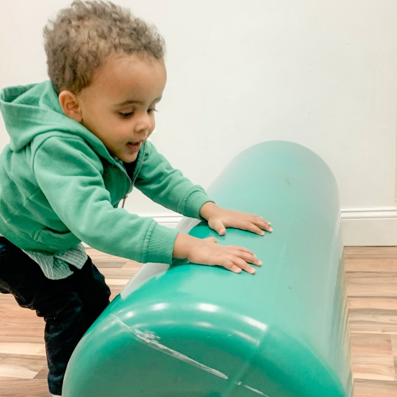 Child pushing therapy bolster.